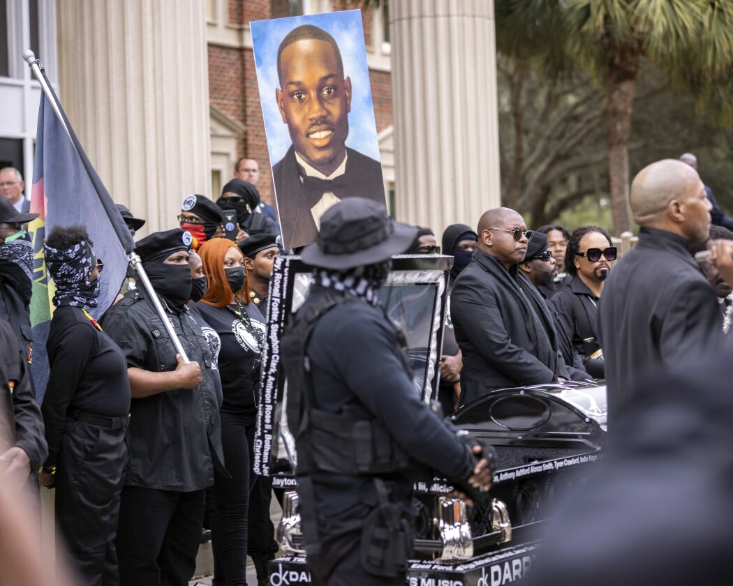 Dozens of members of Black Lives Matter and the Black Panthers, as well as other protesters, gathered outside the Glynn County (Ga.) Courthouse on Monday, Nov. 22, 2021, holding aloft a picture of Ahmaud Arbery. Travis McMichael, his father, Gregory McMichael, and William “Roddie” Bryan, the three men on trial, are charged with the February 2020 slaying of 25-year-old Arbery.